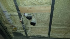 Foam insulation in the wall around a plumbing rough-in.